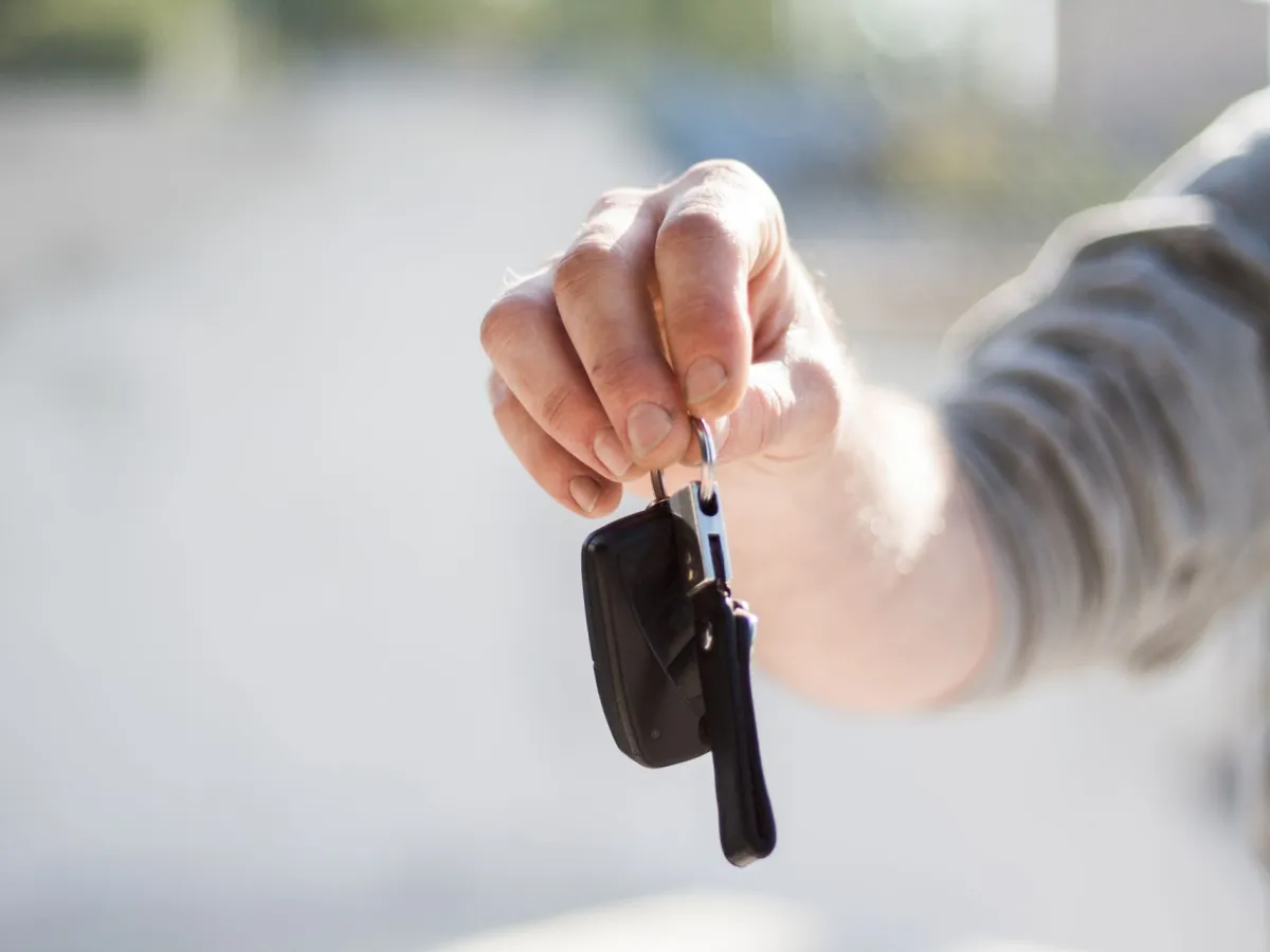 A hand holding out a car key